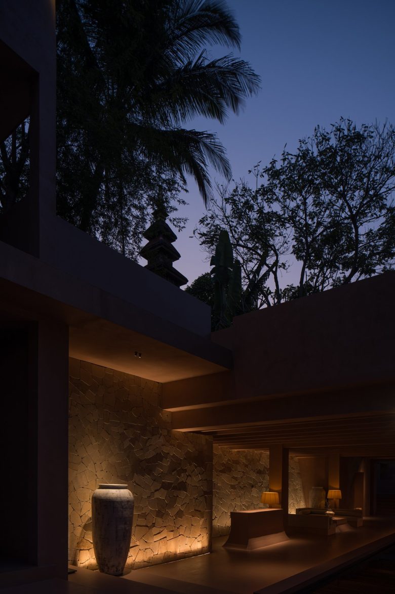 Вечерний внутренний двор с подсветкой каменной стены и большой вазой ALAN RESORT