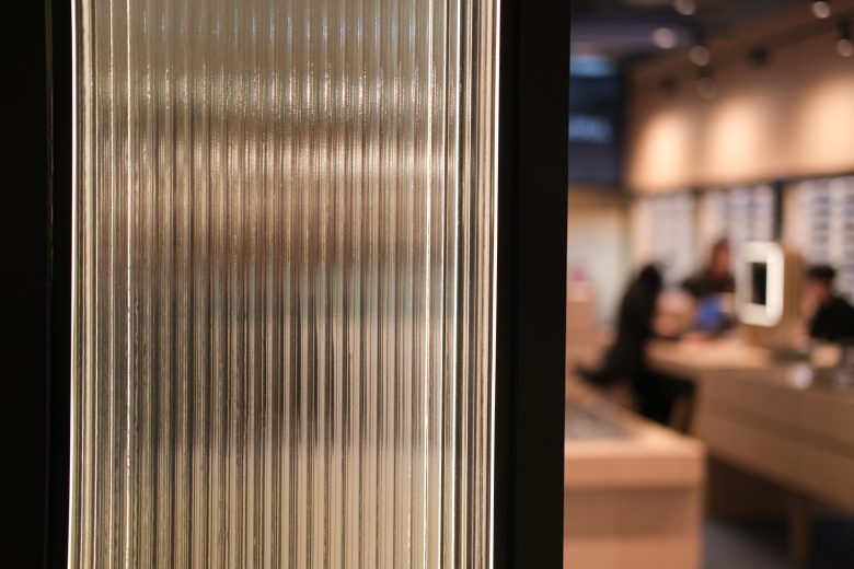 Фактура рифленого стекла с подсветкой, интерьер в расфокусе 1001 Optometry store design