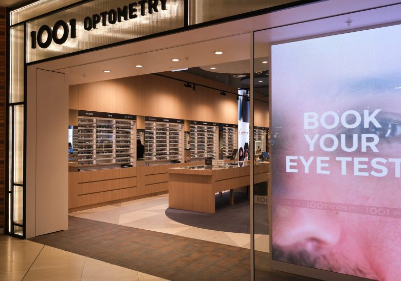 Входная витрина с надписью BOOK YOUR EYE TEST и интерьер 1001 Optometry store design