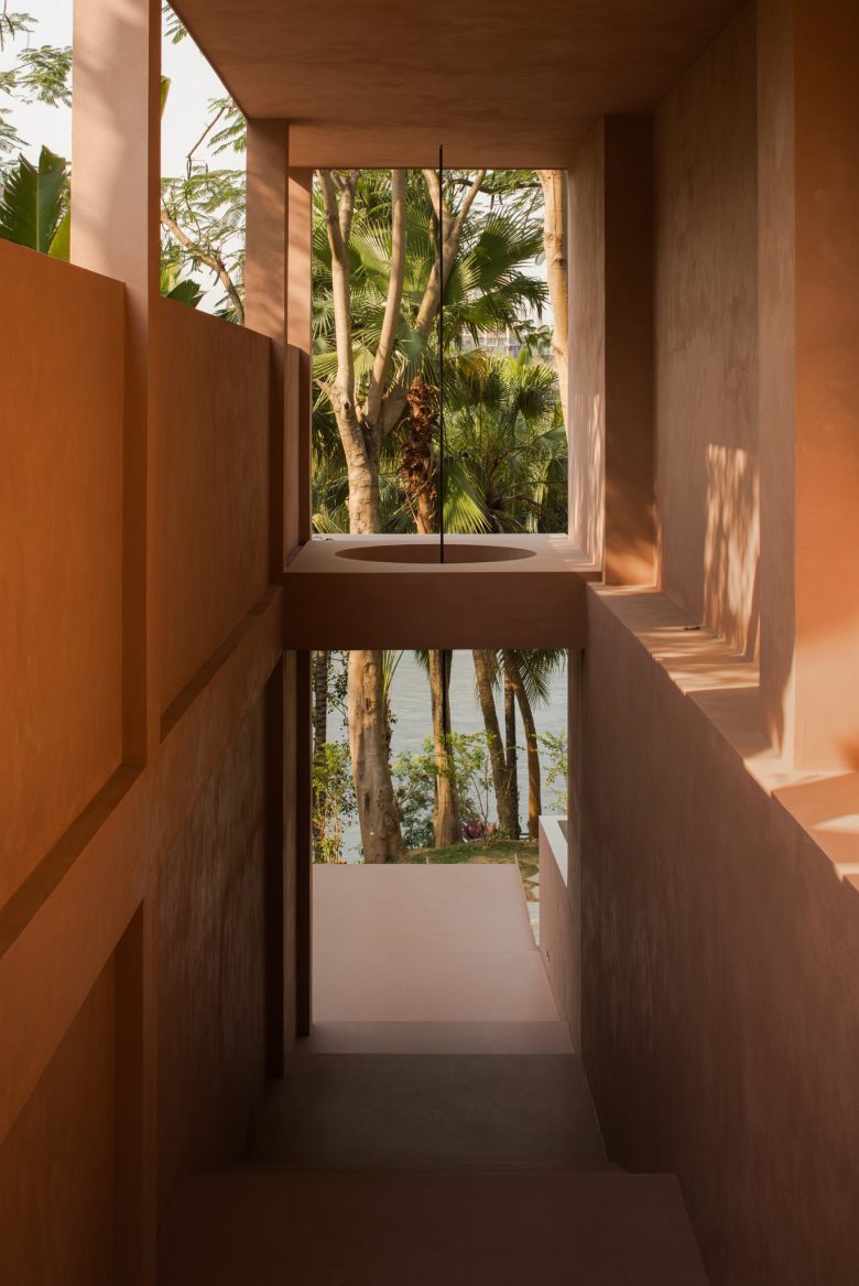 Лестничный пролет с терракотовыми стенами и квадратным проемом с видом на пальмы ALAN RESORT