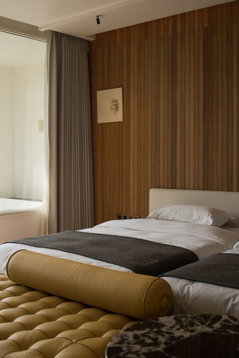 Кровать у деревянной реечной стены с мягкой банкеткой в изножье ALAN RESORT