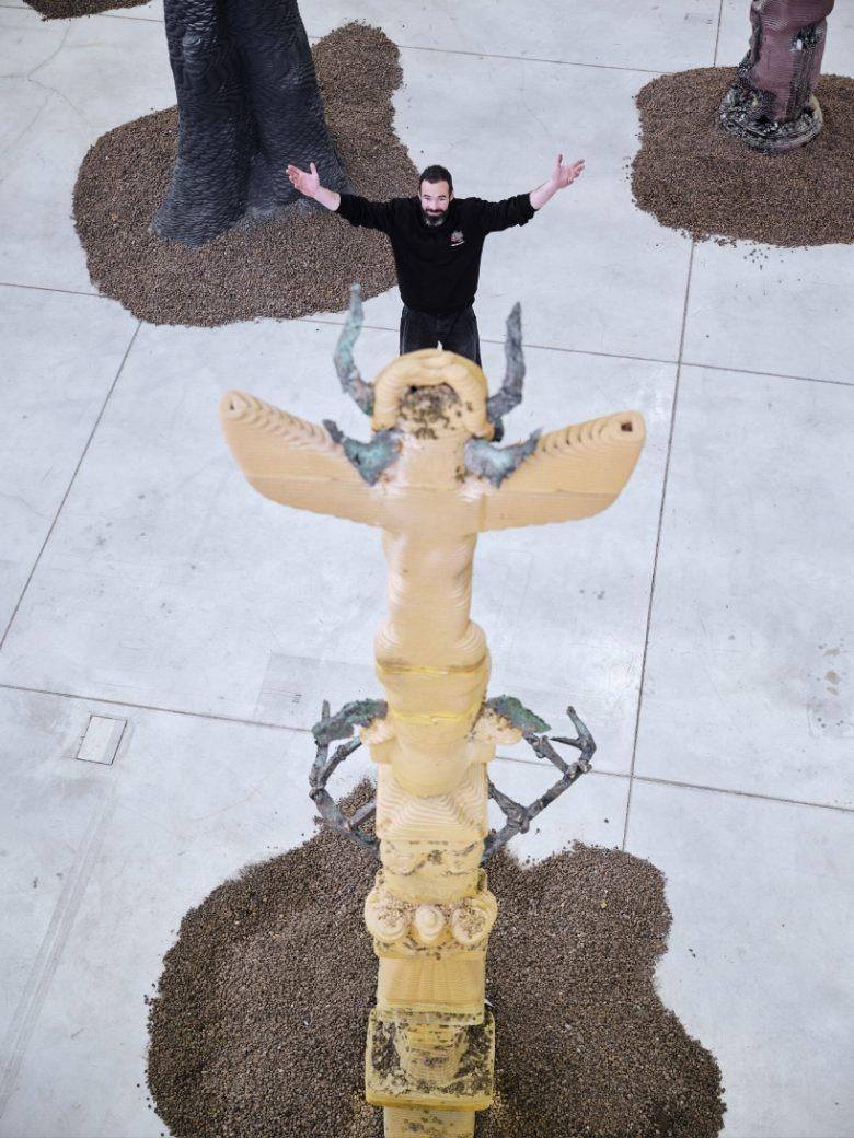 Человек возле золотой скульптуры вид сверху The Virtues and Vices of Our Time installation