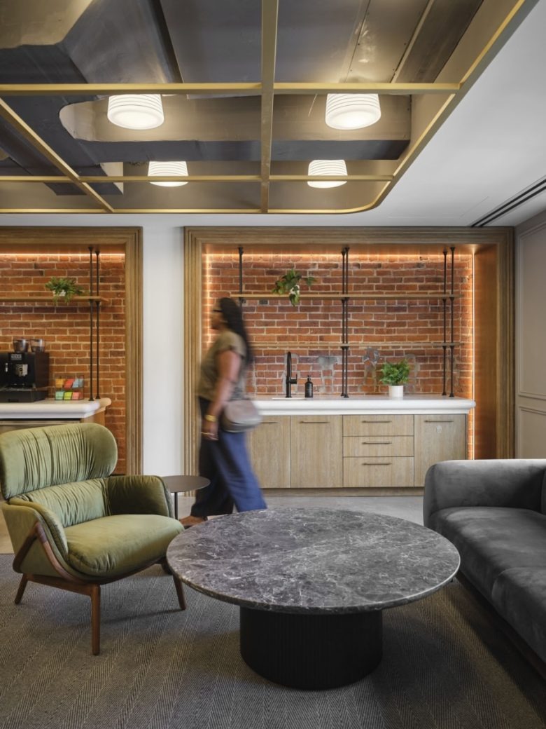 Лаунж зона с кирпичной стеной и кухней Opella Offices