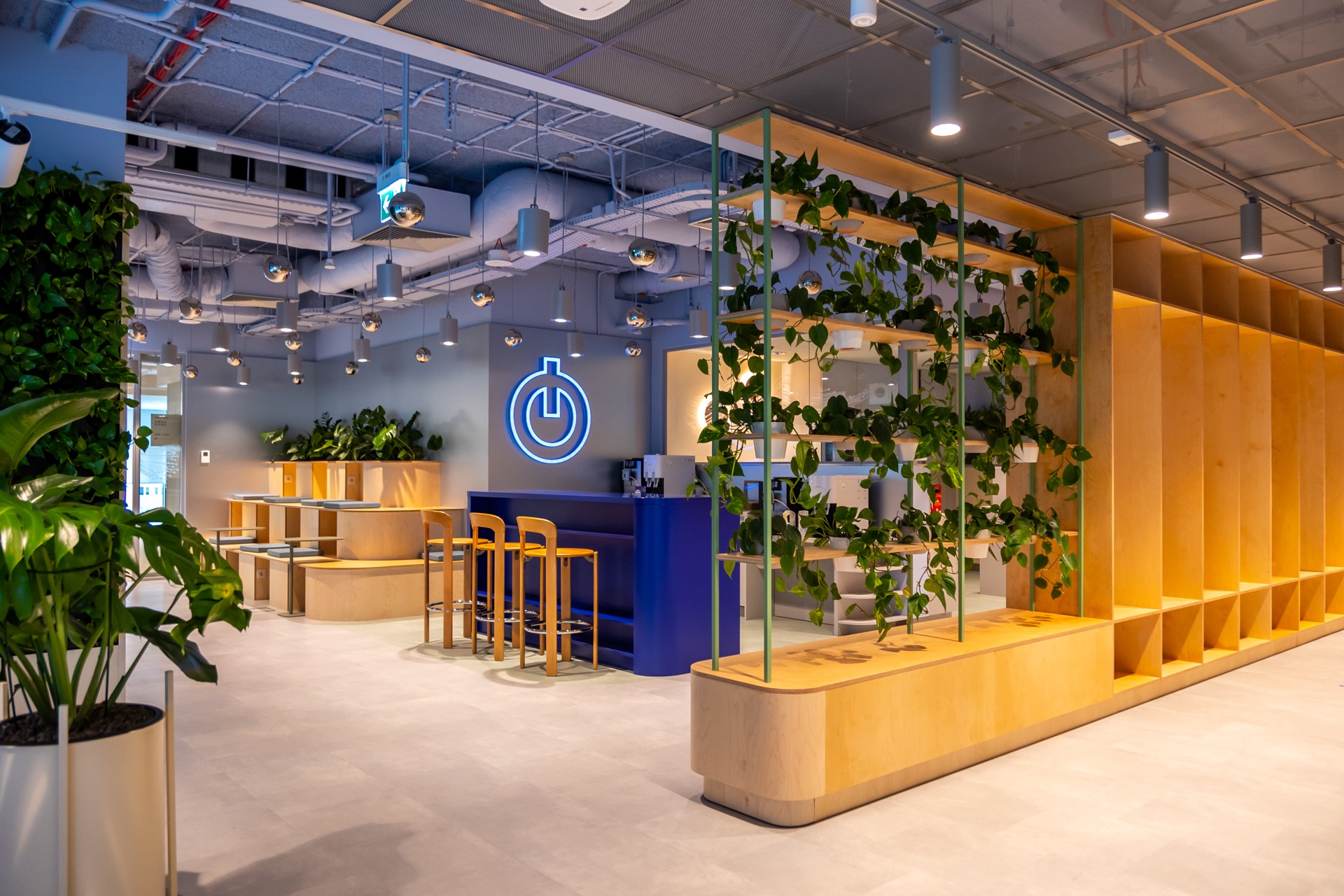 Лаунж-зона с растениями, стеллажом и синей стойкой Ørsted office