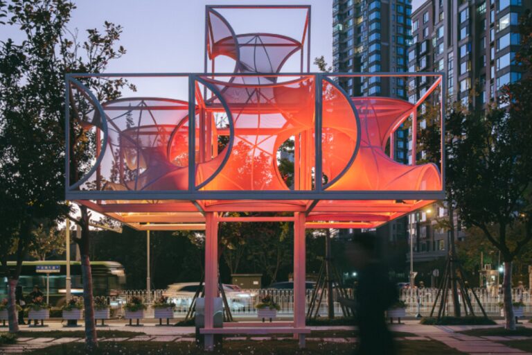 Общий вечерний вид павильона среди деревьев Curly Cube