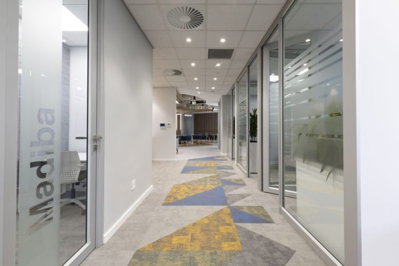 Офисный коридор со стеклянными перегородками и геометрическим ковром Eppendorf Offices