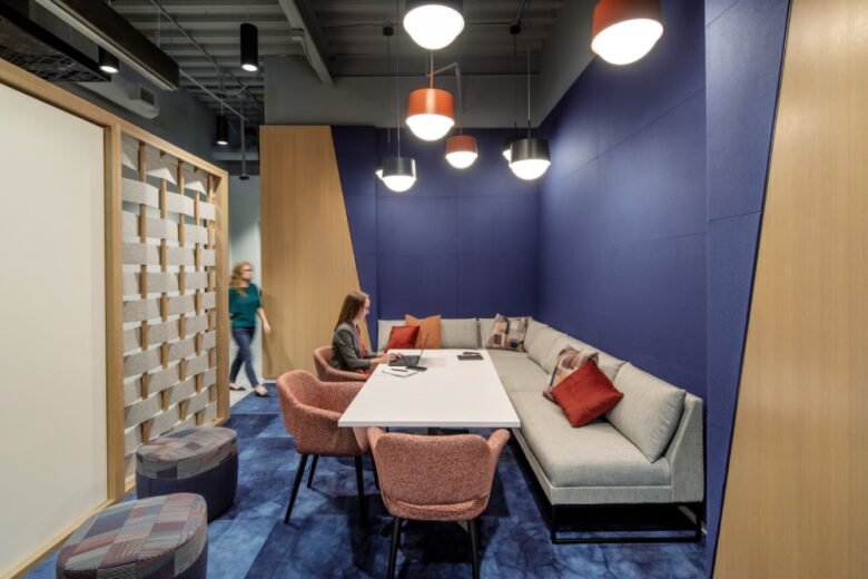 Переговорная ниша с синей стеной, диваном и общим столом.