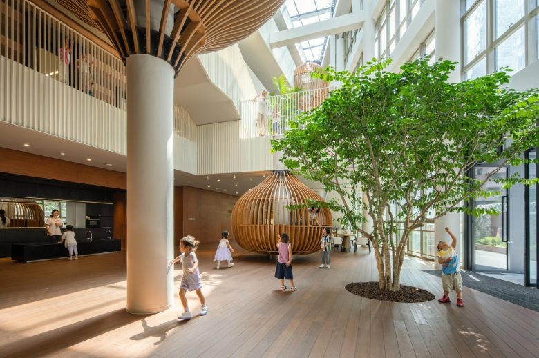 Светлый атриум с деревянными конструкциями и детьми Cheer Kindergartenchiatric Clinic