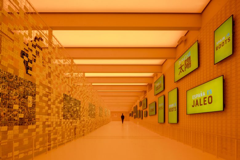 оранжевый павильон Spanish Pavilion at Expo Osaka 2025 с постерами на стене